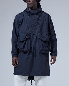 The Indigo C/N Anorak is a lightweight overcoat. The fabric is a cotton and nylon blend. The Indigo C/N Anorak features a hood with a drawcord, half-zip closure, a D ring, two bust pockets, and a fishtail hem. The Indigo C/N Anorak is designed with a looser fit, with the hem hitting just above the knee. We recommend taking your normal size for an oversized fit. The model stands 6' and wears size M. Long Parka, Customer Stories, Snow Peak, Brace Yourself, Bellows, History Design, D Ring, Above The Knee, Half Zip