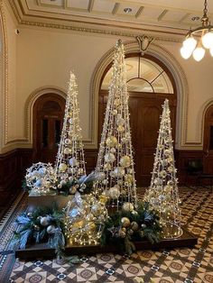 three christmas trees are in the middle of a room