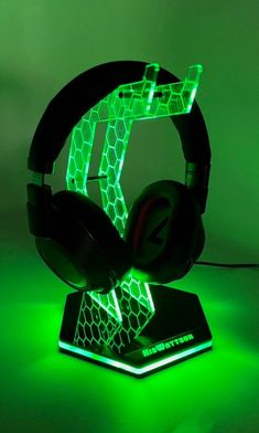 a pair of headphones sitting on top of a green light stand in front of a dark background