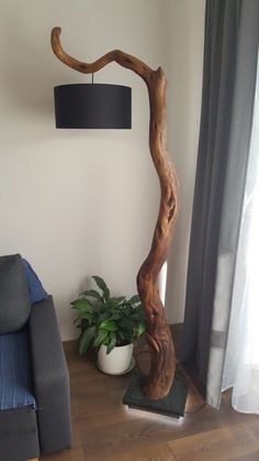 a living room with a couch, chair and wooden tree trunk lamp on the floor