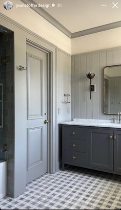 a bathroom with gray cabinets and checkered flooring on the walls, along with a large mirror