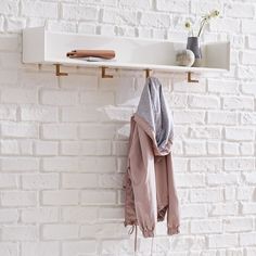 a white brick wall with a shelf and coat rack