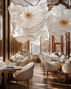 an elegant dining room with large white flowers hanging from the ceiling