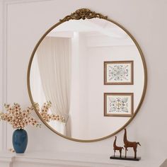 a mirror sitting on top of a mantle next to a vase