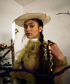 a woman in a hat and dress is posing for the camera