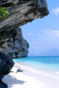 the beach is clear and blue with some rocks on it's sides, as well as an ocean view