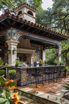 an outdoor kitchen and dining area is shown in this backyard garden setting with colorful tiles on the walls