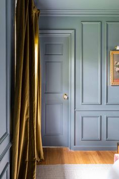 an empty room with blue walls and wood flooring in the foreground is a painting on the wall