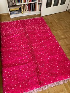 a pink rug on the floor in front of a bookshelf