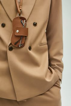 a person wearing a tan suit with a brown belt around their waist and a cell phone in the pocket