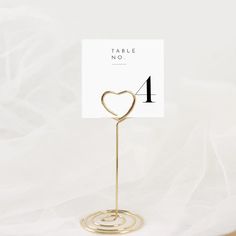 a place card holder with a heart on it and a table number in the middle