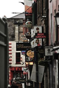 there are many signs on the side of this street that is lined with buildings and shops