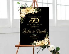 an easel with flowers and greenery on it is displaying the 50th anniversary sign