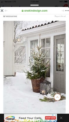 a small christmas tree sitting in front of a white house with snow on the ground