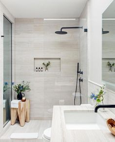 a bathroom with a walk in shower next to a white sink and wooden stools