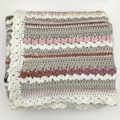 a crocheted dishcloth is shown on a white surface with pink and brown stripes