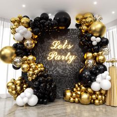 black and gold balloon arch with let's party sign in the center surrounded by balloons