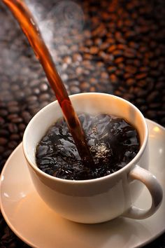 coffee being poured into a cup on a saucer