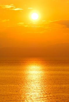 the sun is setting over the ocean with calm water