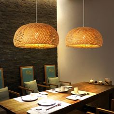 a dining room table with place settings and two hanging lights over the top of it