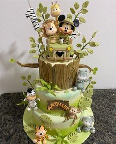 a three tiered cake decorated with mickey mouses and other animal figurines