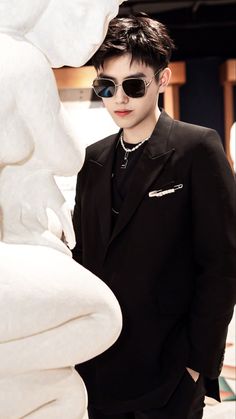 a man wearing sunglasses standing next to a white sculpture