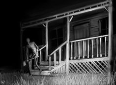 a creepy figure standing on the porch of an old house at night with grass in front of it