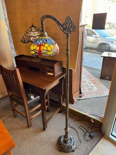 a lamp sitting on top of a wooden desk next to a window