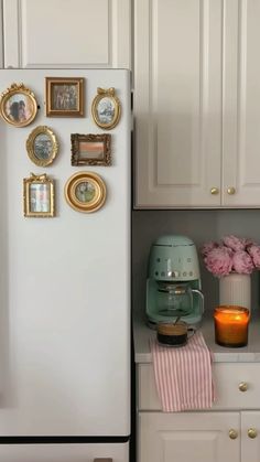 a white refrigerator freezer sitting inside of a kitchen next to a wall with pictures on it