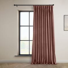 a pink curtain hanging in front of a window with a wooden floor and framed pictures on the wall