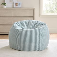 a blue bean bag chair sitting on top of a white rug next to a dresser