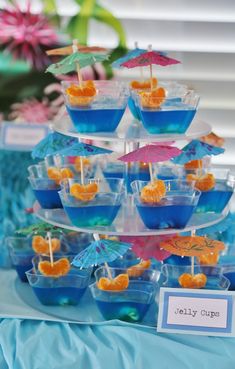 a blue table topped with cups filled with orange slices and umbrellas on top of it