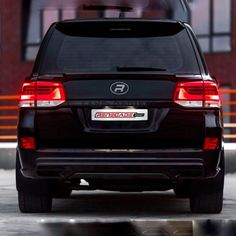 the back end of a black suv parked in front of a building