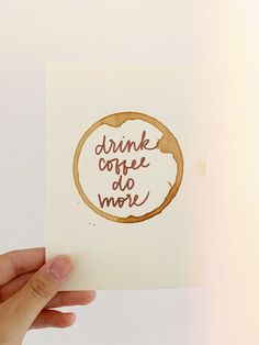 a hand holding up a piece of paper that says drink coffee do more