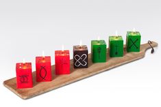 seven candles are arranged on a wooden board