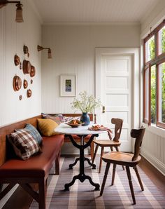 a table with two chairs and a bench in front of a window next to a door