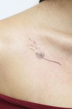 a woman with a tattoo on her chest holding a dandelion