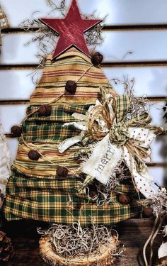 a plaid christmas tree with a red star on top and ribbons around the base, sitting on a wooden table