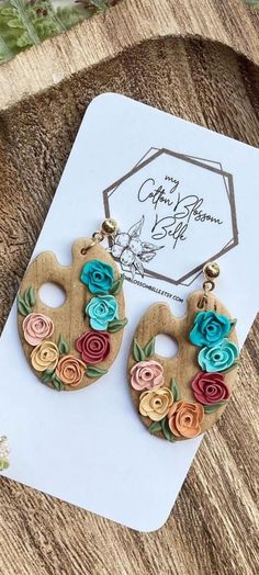 the earrings are made out of wood and decorated with colorful flower designs on it's sides