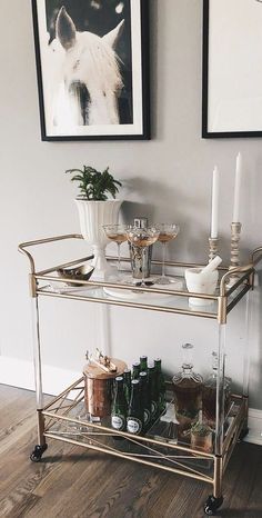 a bar cart with drinks on it next to a christmas tree and two framed pictures