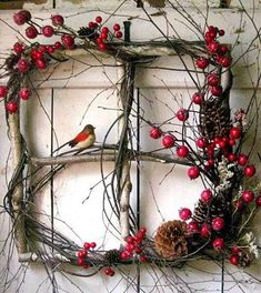 a wreath made out of branches and berries with a bird sitting on the branch next to it