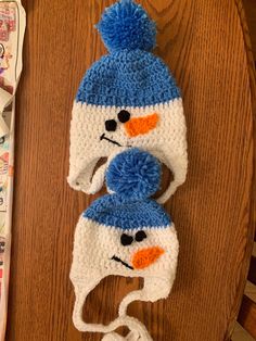 two crocheted hats on top of a wooden table