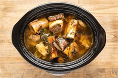 a stew in a crock pot on a wooden table