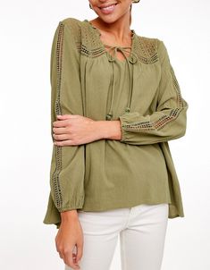 L Love Gauze fabric blouse top with neck self tie and lace sheer insets on shoulders and sleeves. Long sleeves, small ruffle neckline, solid color. Slightly high low with a rounded hem front. Elastic cuff. She is such a sweetie!Color: OliveSizes: S-M-L Bust 36-38-40, length 28Our model is 5' 9" 100% Rayon 100% contrast Cotton, hand wash cold, imported O5/LV2380 Casual Long Sleeve Tops With Lace Cuffs, Chic Tops With Lace Cuffs For Spring, Spring Peasant Top, Casual Blouse With Lace Sleeves For Spring, Casual Blouse With Lace Sleeves For Brunch, Bohemian Tops With Lace Sleeves For Fall, Fall Casual Blouse With Lace Cuffs, Casual Fall Blouse With Lace Cuffs, Spring V-neck Top With Lace Cuffs