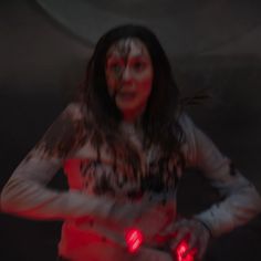 a woman with red lights on her body and hands is standing in front of a dark background