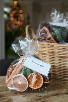 a basket filled with sliced oranges and cinnamon on top of a wooden table next to a christmas tree