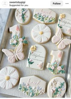 decorated cookies in the shape of flowers and butterflies are on a tray with white frosting