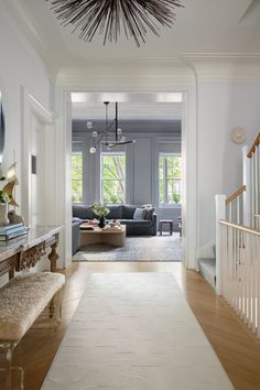 a living room filled with furniture and a white rug on top of a hard wood floor