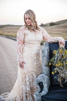 a woman in a long dress standing next to a suitcase with flowers on the back