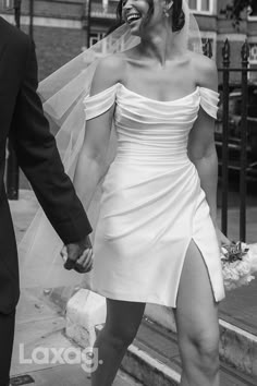 a bride and groom walking down the street holding hands with each other in black and white